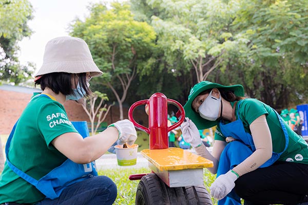 Các tình nguyện viên BASF Việt Nam, người lớn và trẻ em, trang trí sân chơi và các thiết bị chơi ngoài trời.
