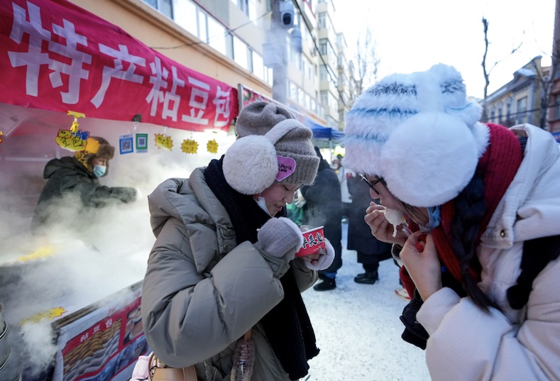 Khách du lịch thử món bánh hấp nhồi đậu tại một khu chợ buổi sáng ở Cáp Nhĩ Tân. Ảnh: Xinhua