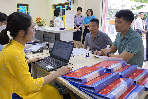 Cán bộ bưu điện hướng dẫn người dân nộp thủ tục hành chính qua Cổng dịch vụ công trực tuyến.