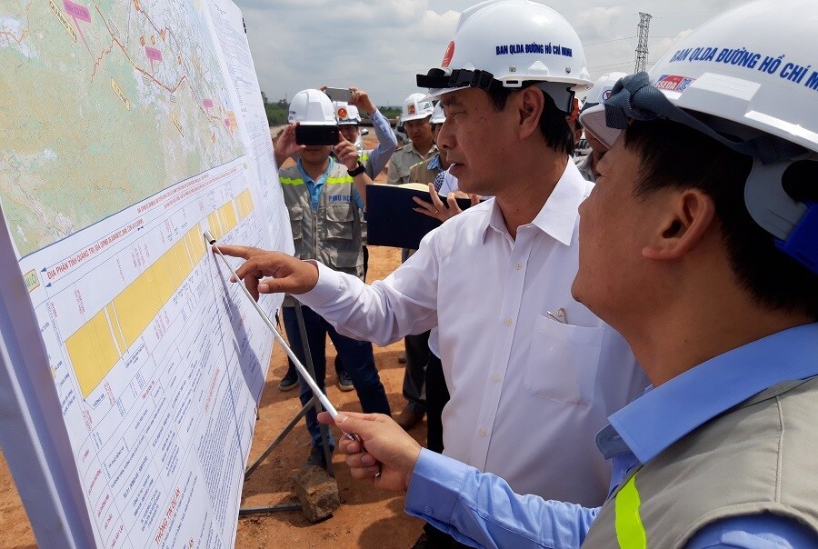Thứ trưởng Lê Đình Thọ (áo trắng, đội mũ) trao đổi với lãnh đạo Ban quản lý Dự án đường Hồ Chí Minh và các nhà thầu về các vướng mắc trên công trường.