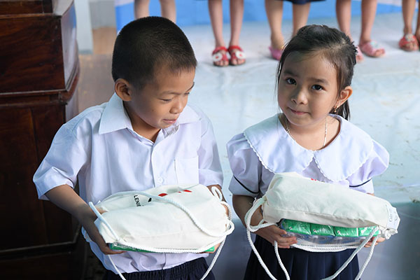 Các em học sinh vui mừng với món quà lưu niệm được trao tặng, trong đó có sản phẩm giày do Khoan Nghị tài trợ, có sử dụng nguyên liệu của BASF.