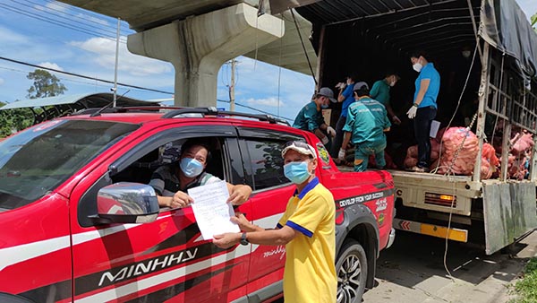 Thành viên Đội xe xung kích nhận giấy vận chuyển hàng hóa đến điểm phòng chống dịch trong địa bàn TPHCM