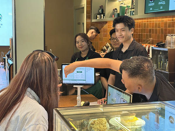 Nh&acirc;n vi&ecirc;n khiếm th&iacute;nh đang hướng dẫn kh&aacute;ch h&agrave;ng đặt m&oacute;n qua m&agrave;n h&igrave;nh tại Signing Store Cao Thắng