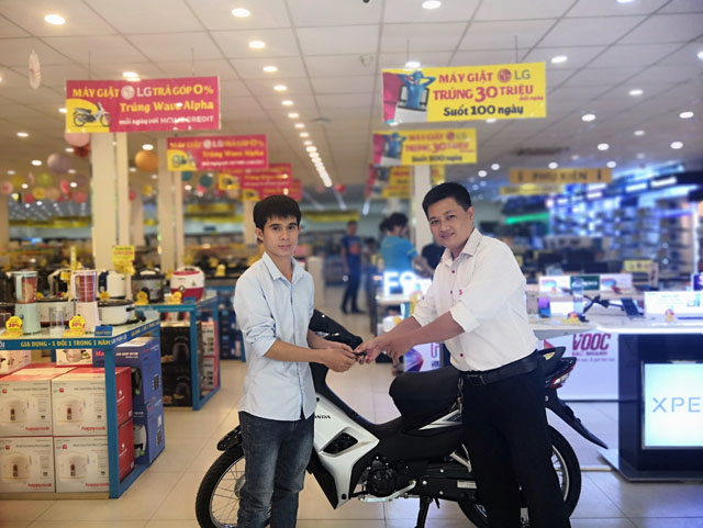 Đại diện công ty Home Credit trao tặng xe Honda Wave Alpha cho khách hàng Nguyễn Thành Tính (giữa)