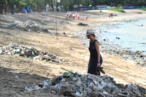 Khách du lịch đi giữa những đống rác được thu gom trên bãi biển Kuta gần Denpasar, Bali. Ảnh: AFP