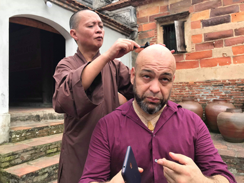 Flores được sư trụ trì chùa Bổ Đà cạo tóc trước khi quay phim.