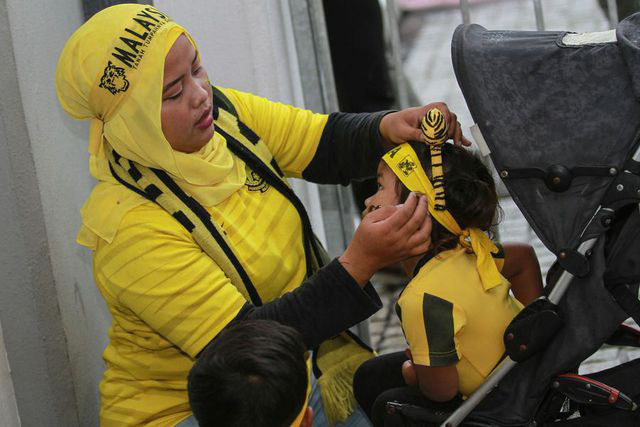 Một cổ động viên nữ của Malaysia quấn khăn cho một em bé để vào cổ vũ cho tuyển Malaysia  Nhìn lại thất bại cay đắng của tuyển Thái Lan trên sân của Malaysia - 3