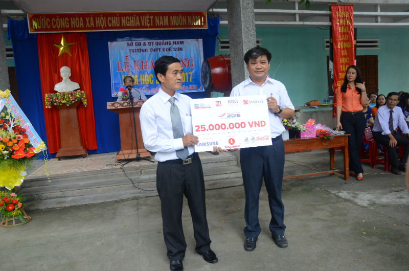 Đại diện báo Đầu tư Khu vực miền Trung (bên phải) trao bảng tượng trưng giá trị học hổng cho lãnh đạo trường THPT Quế Sơn. 