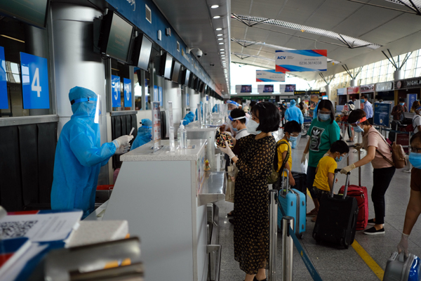 Nhân viên sân bay thực hiên quy trình bảo hộ nghiêm ngặt khi làm thủ tục cho du khách