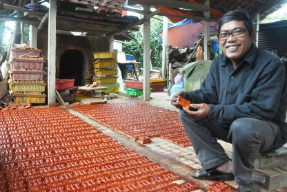 Ông Nguyễn Văn Chín bên những tượng ông Táo chuẩn bị bán cho người mua.