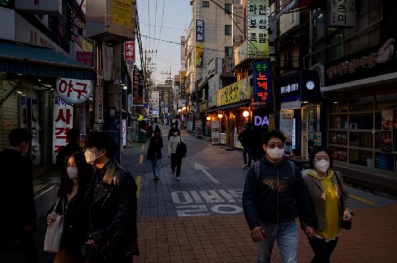 Người dân Hàn Quốc đi bộ dưới đường phố Seoul hôm 24/3. Ảnh: AFP