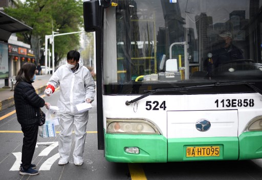 Nhân viên xe buýt kiểm tra thân nhiệt hành khách tại Vũ Hán hôm 30/3. Ảnh: AFP