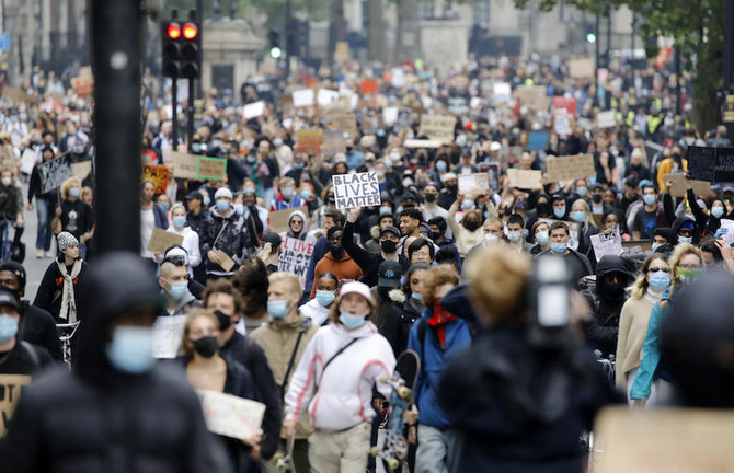 Một số nhà hoạt động đeo khẩu trang hoặc khăn che mặt phòng dịch Covid-19, cầm biểu ngữ khi tham dự cuộc tuần hành theo phong trào hoạt động quốc tế “Black Lives Matter” (Người da đen đáng được sống) đến Quảng trường Trafalgar ở London vào ngày 12/6/2020. Ảnh tư liệu: AFP