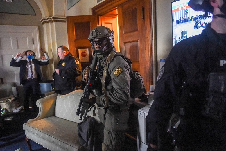 Một thành viên Quốc hội Mỹ giơ tay khi cảnh sát làm nhiệm vụ trấn áp đám đông biểu tình và phá hoại tại Điện Capitol hôm 6/1. Ảnh: AFP