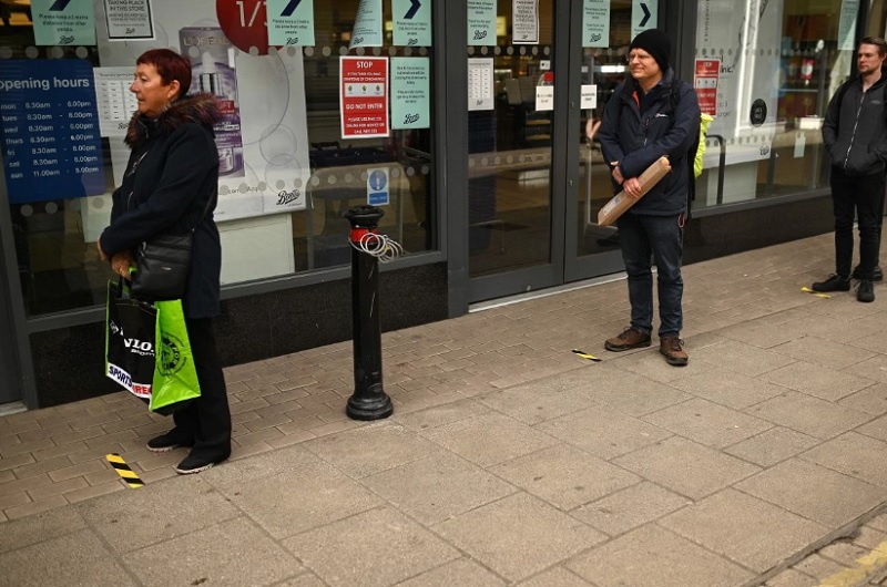 Người mua hàng tại Anh tuân thủ quy định giãn cách xã hội. Ảnh: AFP