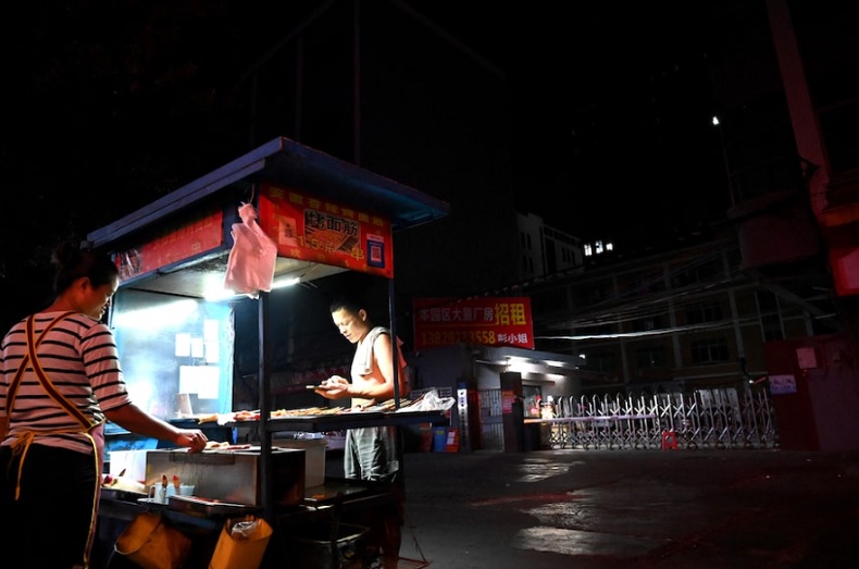 Một người bán hàng thực phẩm trước lối vào của một khu công nghiệp ở thành phố Đông Qua, tỉnh Quảng Đông, Trung Quốc - nơi bị ảnh hưởng bởi thiếu điện. Ảnh: AFP 