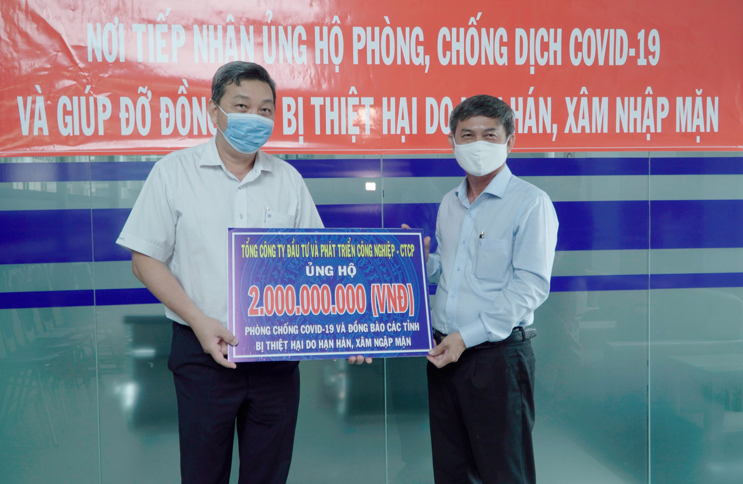 Ông Nguyễn Văn Lộc (đứng bên phải) nhận số tiền ủng hộ từ đại diện Tổng Công ty Becamex IDC.
