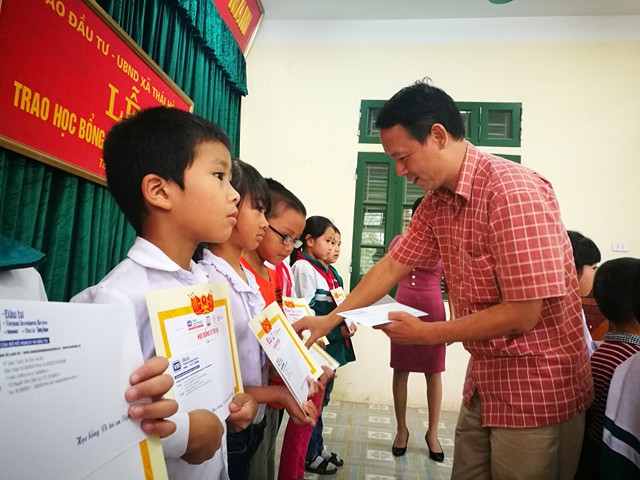 Ông Văn Đức Hiệp, Phó chủ tịch Công đoàn - Trưởng phòng Kế toán tài vụ Báo Đầu tư trao học bổng cho các em học sinh trường Tiểu học Thái Hòa.