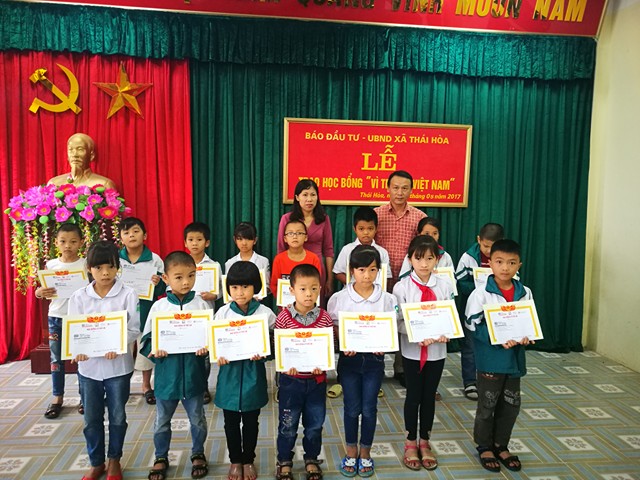 Ông Văn Đức Hiệp và cô Ngô Thị Lệ Hằng, Phó Hiệu trưởng trường Tiểu học Thái Hoà trao học bổng và chụp ảnh cùng các em học sinh.