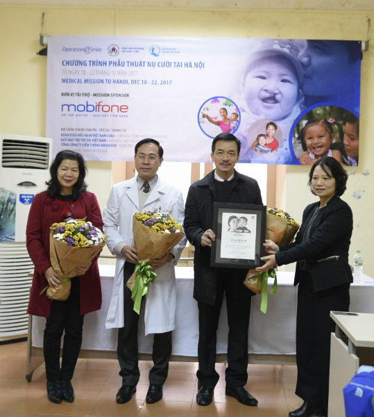 Ông Nguyễn Mạnh Hùng, Phó TGĐ Tổng công ty Viễn thông MobiFone nhận hoa và bằng  từ đại diện Operation Smile Việt Nam, bà Nguyễn Thị Hải Đức, Giám đốc chương trình Operation Smile Việt Nam.