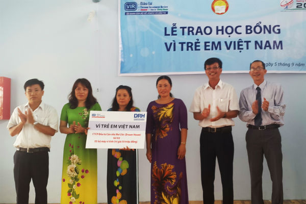 Ông Nguyễn Xuân Phú - Phó Tổng Giám đốc Công ty cổ phần Căn nhà Mơ ước (Dream House) trao biển tượng trưng 5 bộ máy tính cho đại diện 2 trường Tân Phước 1 và Tân Phước 2