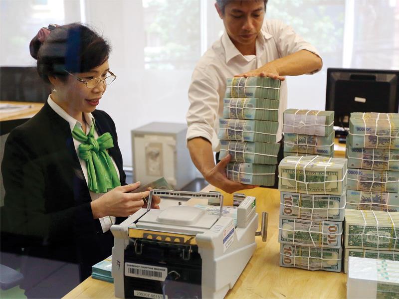 Cần nâng lãi suất gửi USD để huy động nguồn lực trong dân. Trong ảnh: Hoạt động nghiệp vụ tại Vietcombank.