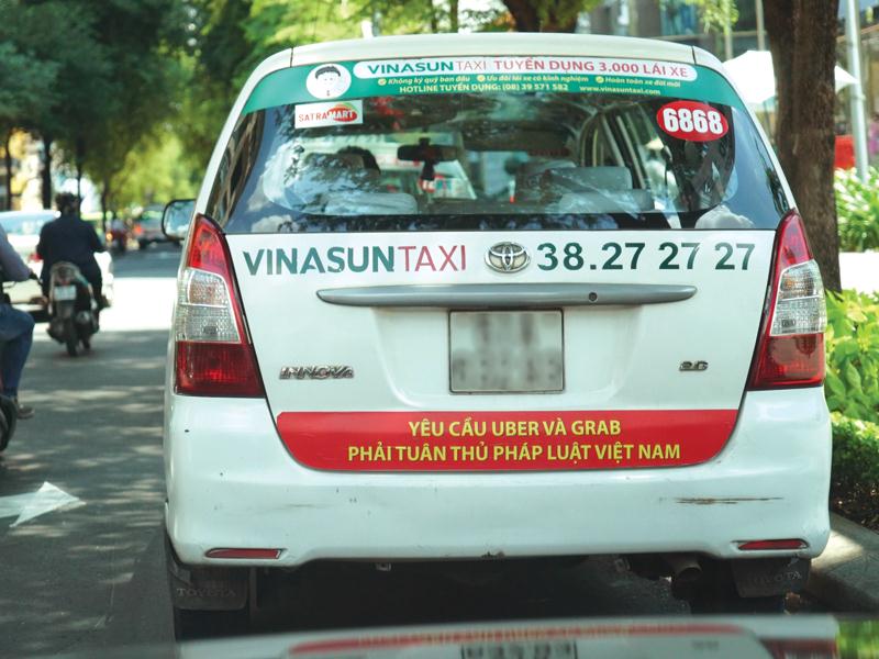 Nhiều tài xế taxi đã dán decal sau xe để phản đối Uber, Grab vì bị tranh mất khách.