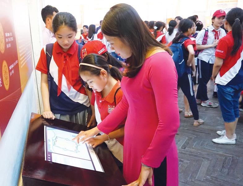 Du khách trải nghiệm màn hình diễn giải lịch sử tại Khu trung tâm Hoàng thành Thăng Long - Hà Nội.
