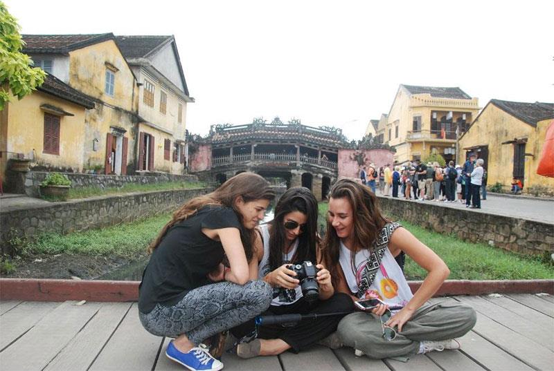 Trước biểu tượng Chùa Cầu, du khách nước ngoài thích thúc xem lại hình ảnh Hội An trong máy ảnh do mình chụp. Ảnh: Hà Minh