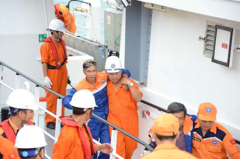 Sức khỏe chưa ổn định, các ngư dân được thyền viên tàu cứu nạn dìu lên bờ.