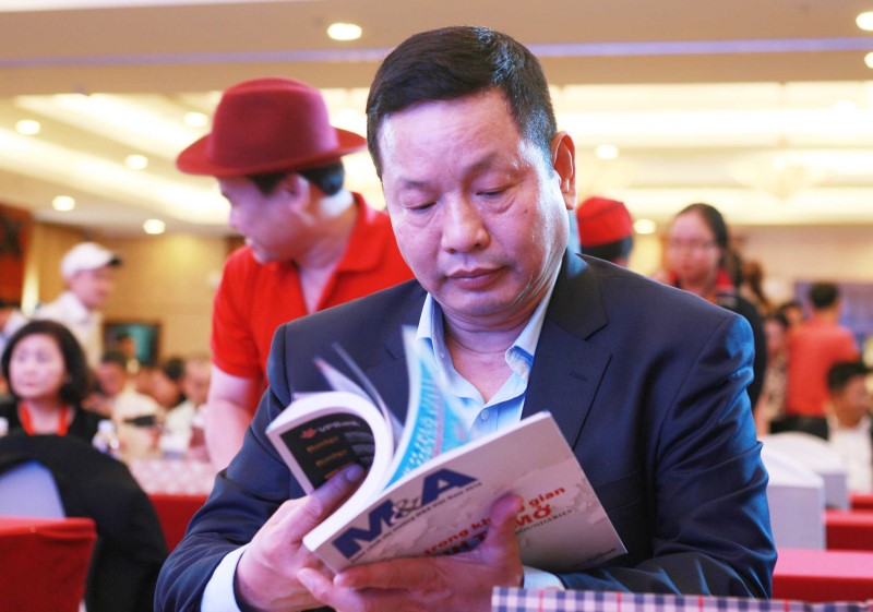 Ông Trương Gia Bình, chủ tịch tập đoàn FPT tranh thủ đọc lướt qua những thương vụ mua bán trên Đặc san M&A 2016 do Báo Đầu Tư phát hành trước giờ nói chuyện với các doanh nghiệp.