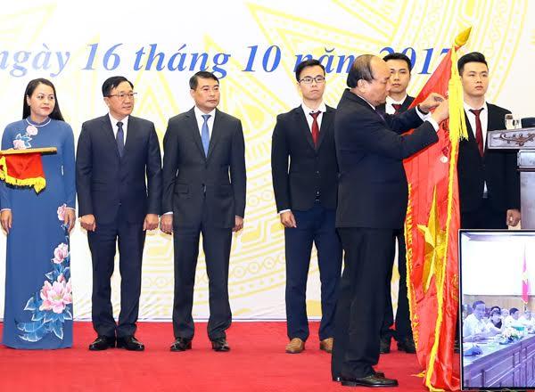 Ủy viên Bộ Chính trị - Thủ tướng Chính phủ Nguyễn Xuân Phúc gắn Huân chương Lao động hạng Nhất lên lá cờ truyền thống của VBSP (Ảnh VBSP)