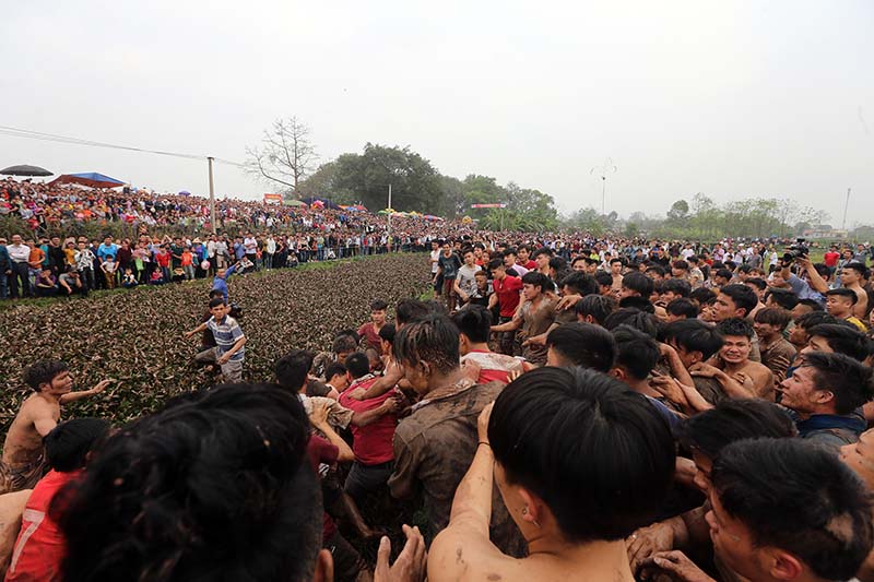 Đám đông đẩy nhau lao về phía mương nước đen ngòm trong sự reo hò cổ vũ nhiệt tình của người xem