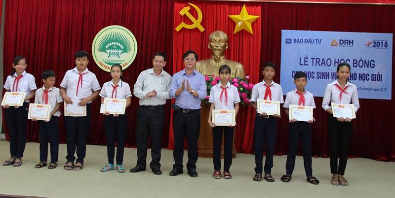 Ông Nguyễn Hồng (thứ 5 từ phải qua), Phóng Tổng biên tập Báo Đầu tư cùng ông Văn Quý Ngọc, Chủ tịch UBND huyện Hàm Tân, trao học bổng cho các em học sinh