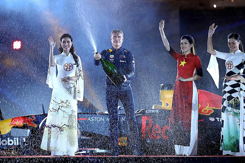 David Coulthard - cựu tay đua F1 người Anh, từng giành chiến thắng 13 giải Grand Prix trong suốt 15 mùa thi đấu. Hiện tại, anh là một diễn giả, bình luận viên và nhà báo. David Coulthard đang thực hiện nghi thức bật champagne ăn mừng chiến thắng quen thuộc ở các chặng đua công thức 1.