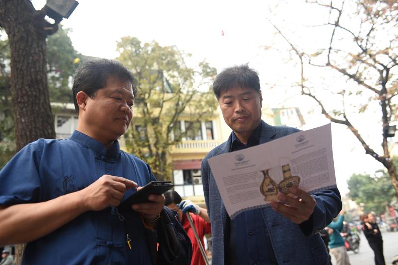 2 du khách đến từ Hàn Quốc đọc tờ thông tin về gốm Chu Đậu, cho biết đã chọn đến du lịch Việt Nam nhân dịp diễn ra Hội nghị thượng đỉnh Mỹ - Triều. 