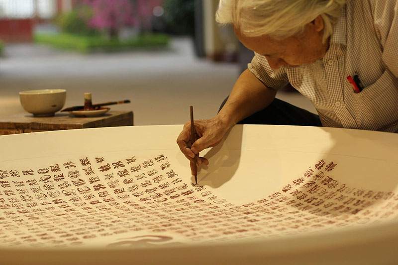 Ông Lê Thiên Lý viết 1.000 chữ Long bằng thư pháp trên đĩa gốm Chu Đậu.
