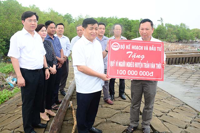 Bộ trưởng Bộ Kế hoạch và Đâu tư Nguyễn Chí Dũng trao tượng trưng tiền để hỗ trợ cho người nghèo huyện Trần Văn Thời.