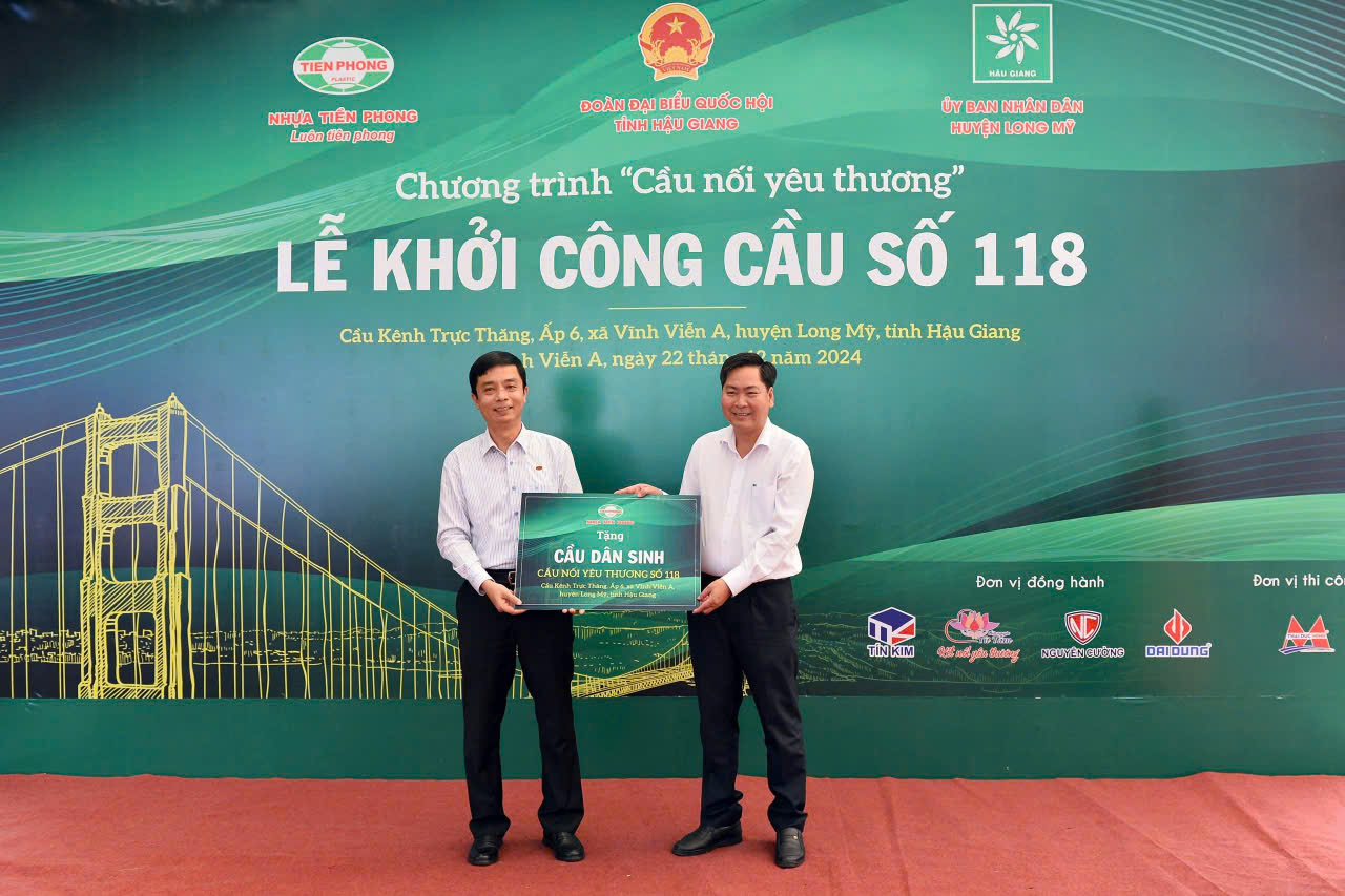 Ông Trần Ngọc Bảo, Thành viên HĐQT, Phó Tổng giám đốc Công ty Nhựa Tiền Phong (bên trái) trao bảng tượng trưng tặng cầu dân sinh cho ông Nguyễn Vũ Trường, Chủ tịch UBND huyện Long Mỹ