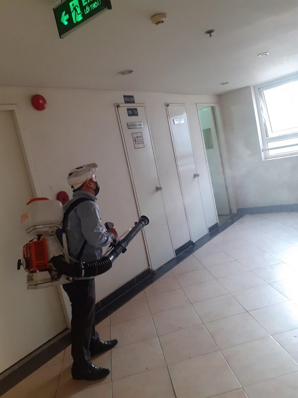 Nhân viên vệ sinh đang xịt thuốc khử trùng tại khu vực hành lang của chung cư