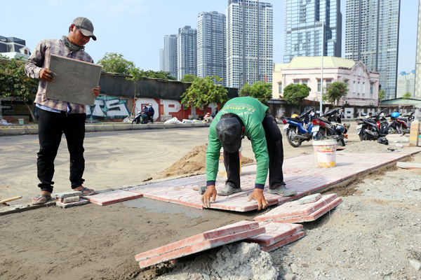 Công nhân đang lát gạch vỉa hè tại khu vực cầu vượt Nguyễn Hữu Cảnh