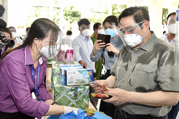 Thủ tướng xem các loại nhu yếu phẩm, thuốc men... trong túi an sinh sẽ được cung cấp cho người dân trong chuyến kiểm tra sáng ngày 26/8. (Ảnh: VGP)