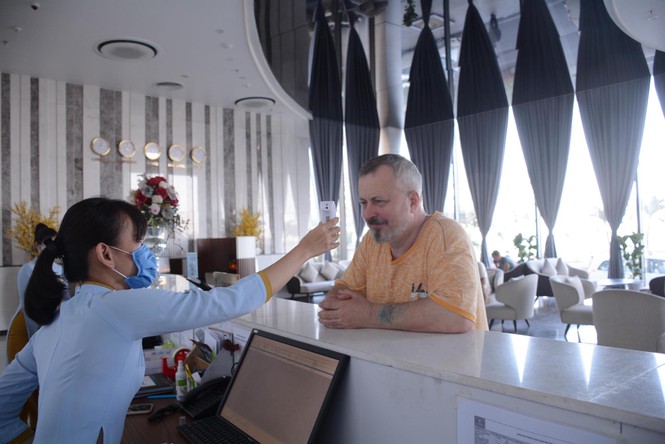 Nhân viên một khách sạn tại Khánh Hòa kiểm tra thân nhiệt cho du khách tại quầy đón tiếp