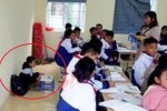 Một học sinh bị cô giáo phạt ngồi dưới sàn học bài vì quên khăn quàng đỏ